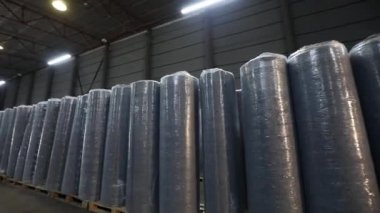 Polyesterli uzun ışıklı sıra. Fabrikadaki depo. Sentetik el değmemiş kumaş deposu