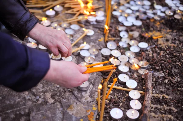 As pessoas acendem velas em um pátio da igreja — Fotografia de Stock