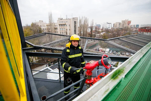 Feuerwehrmann hält eine Brandbekämpfungsanlage (Hydrant) an einem Krankenhaus — Stockfoto