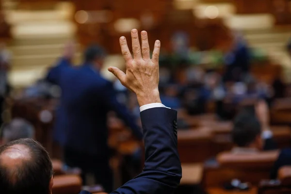 Члены парламента Румынии голосуют, поднимая руки — стоковое фото