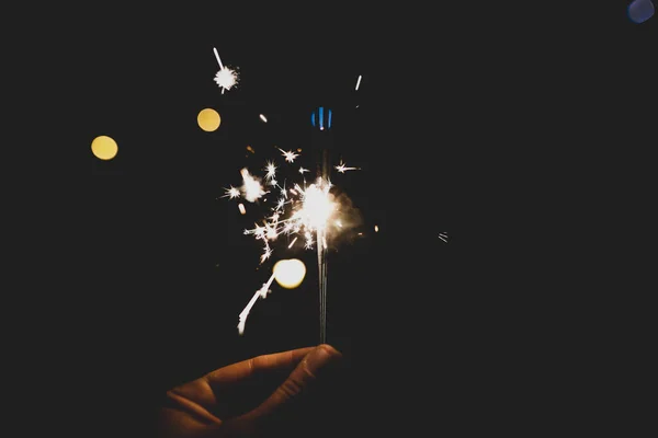 Dettagli con la mano di un uomo che tiene scintillanti fuochi d'artificio a mano . — Foto Stock