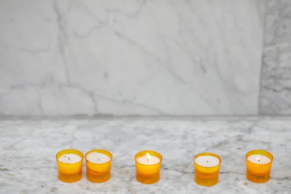 White lit candles on a white block of white marble — 스톡 사진