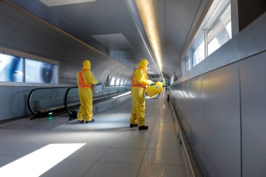 Otopeni, Romania - February 25, 2020: People wearing protective suits spray disinfectant chemicals on the Henri Coanda International Airport to prevent the spreading of the coronavirus.