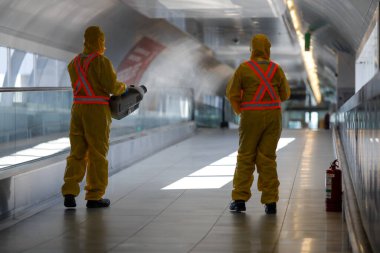Otopeni, Romania - February 25, 2020: People wearing protective suits spray disinfectant chemicals on the Henri Coanda International Airport to prevent the spreading of the coronavirus.
