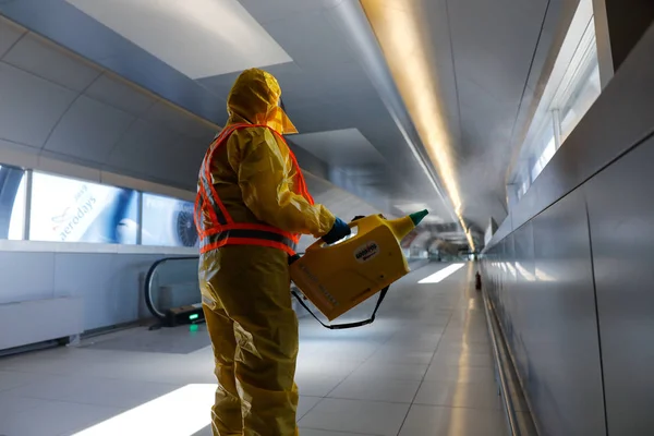 Otopeni, Romania - February 25, 2020: People wearing protective suits spray disinfectant chemicals on the Henri Coanda International Airport to prevent the spreading of the coronavirus.