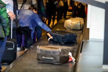 Otopeni, Romanya - 25 Şubat 2020: Henri Coanda Uluslararası Havaalanı 'ndaki bagaj bandından kadın bagajını kaldırdı.