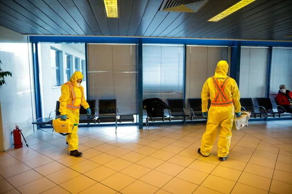 Otopeni, Romania - February 25, 2020: People wearing protective suits spray disinfectant chemicals on the Henri Coanda International Airport to prevent the spreading of the coronavirus.