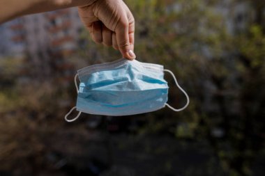 Sığ alan görüntüsü derinliği (seçici odak) burun ve ağız maskesi tutan bir adamın eliyle.