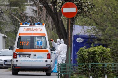 Bükreş, Romanya - 1 Nisan 2020: Covid-19 enfeksiyonu nedeniyle kapalı bir hastanenin bahçesinde koruyucu giysiler giyen Romen sağlık personeli.