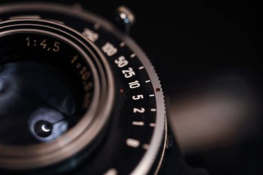 Çok eski bir fotoğraf makinesinin merceğindeki işaretlerle (pozlama süresi ve f-stop) alan resminin makro ve sığ derinliği (seçici odak)).