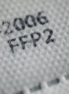 Macro and shallow depth of field image (selective focus) with the texture and inscriptions of a ffp2 anti covid-19 face and nose mask. clipart