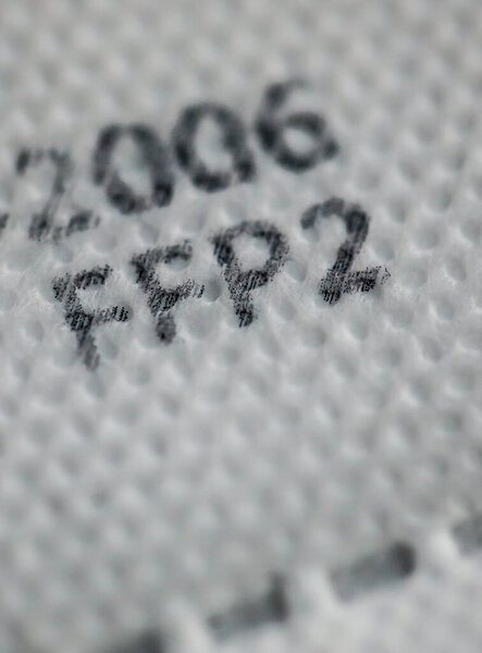 Macro and shallow depth of field image (selective focus) with the texture and inscriptions of a ffp2 anti covid-19 face and nose mask.