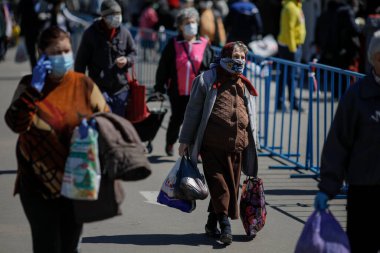 Bükreş, Romanya - 16 Nisan 2020: Koruyucu maskeler takan yaşlılar, Covid-19 salgını sırasında Bükreş 'teki kalabalık bir açık pazarda alışverişlerini yapıyorlar.