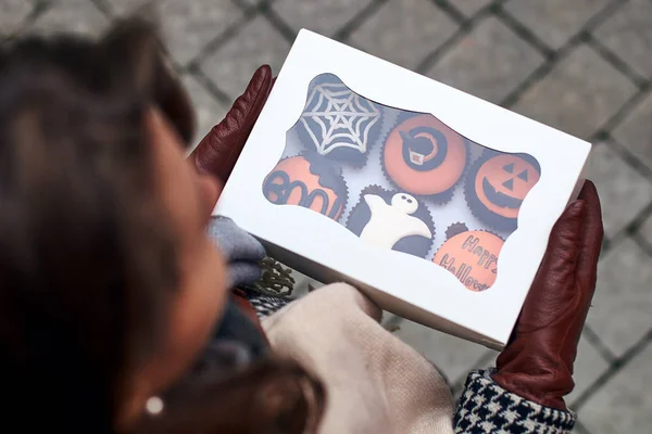 Mujer joven sosteniendo una caja de colores de diferentes cupcakes estilo Halloween — Foto de Stock