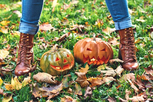 Mujer con botas se levanta sobre las calabazas de Halloween al aire libre en el parque de otoño — Foto de Stock