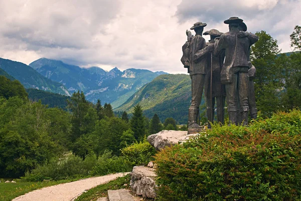 Ribcev Laz, Eslovenia - 4 de julio de 2017: Parque de la ciudad cerca del lago Bohinj con el monumento a cuatro hombres valientes - nativos locales que escalaron la montaña más alta de Triglav en Eslovenia en 1778 . — Foto de Stock