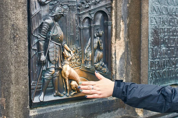 Praga, República Tcheca - 27 de setembro de 2014: Turista está esfregando uma placa de bronze de São João Nepomuks parte do cão da estátua de São João Nepomuk na Ponte Carlos para boa sorte . — Fotografia de Stock