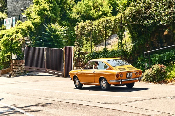 Young man driving yellow vintage Fiat 850 Sport Coupe released circa 1970 in Italy. — Stock Photo, Image