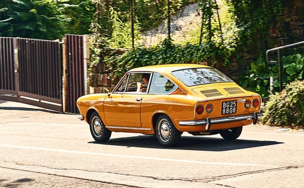 Młody człowiek jazdy vintage żółty Fiat 850 Sport Coupe wydany circa 1970 we Włoszech. — Zdjęcie stockowe