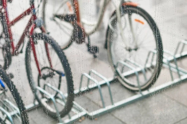 Vista de bicicletas estacionadas através do vidro com gotas de água — Fotografia de Stock