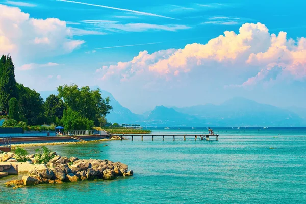 Beautiful landscape view of summer lake Garda in Italy with turquoise water and amazing pink evening clouds — Stock Photo, Image