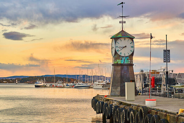 Clock tower on Aker Brygge Dock at the waterfront with marina on background.
