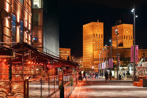 奥斯陆的夜城市看法挪威在 Aker Brygge 船坞与餐馆和市政厅或 Radhuset 在背景上. — 图库照片