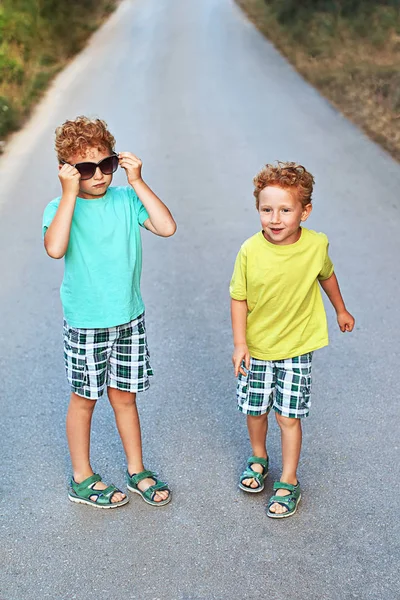Dois meninos encaracolados vermelhos bonitos irmãos estão se divertindo com óculos de sol da mãe — Fotografia de Stock