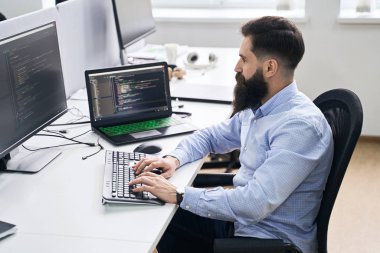 IT ofisinde çalışan bilgisayar programcısı, masa başında oturuyor ve kodluyor, yazılım geliştirme şirketinde ya da başlangıçta bir proje üzerinde çalışıyor.