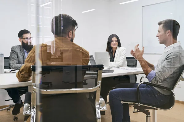 Корпоративная команда и менеджер на встрече в конференц-зале ИТ-компании. Вид через стеклянную стену . — стоковое фото