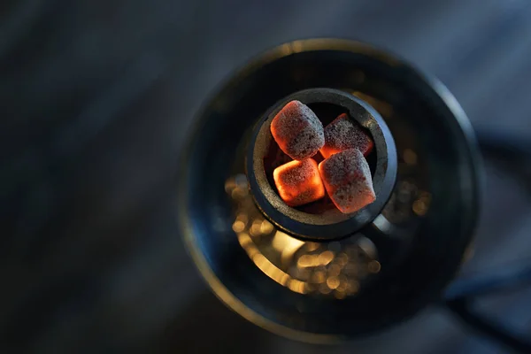 Kırmızı kömürlü Shisha nargile kasesi ve el yapımı tütün. Rahatlamak ve sigara içmek için hindistan cevizi kömürlü modern nargile. Güzel bir Bokeh ve rahat, karanlık bir arka plan. Üst görünüm.