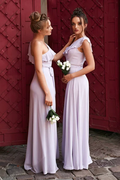 Duas jovens meninas bonitas vestindo um full-length escuro vermelho chiffon  vestido de baile de formatura