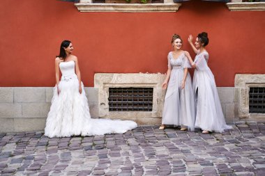 Güzel gelin ve nedimeler zarif, şık, açık gri gri zemin uzunluğunda elbiseleriyle eski güzel Avrupa şehrinde düğün günü eğleniyorlar..