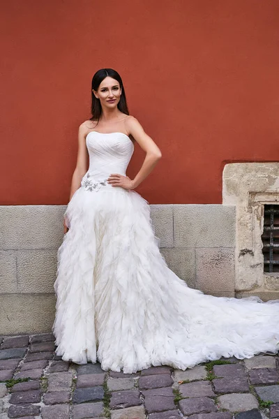 Gyönyörű menyasszony visel gyönyörű elegáns, elegáns, fehér padló hossza ruha régi szép európai város egy esküvő napján. — Stock Fotó