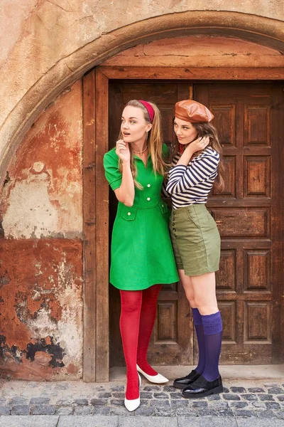Jóvenes hermosas chicas vestidas en estilo retro vintage disfrutando del viejo estilo de vida de la ciudad europea mientras se ven sorprendidas — Foto de Stock