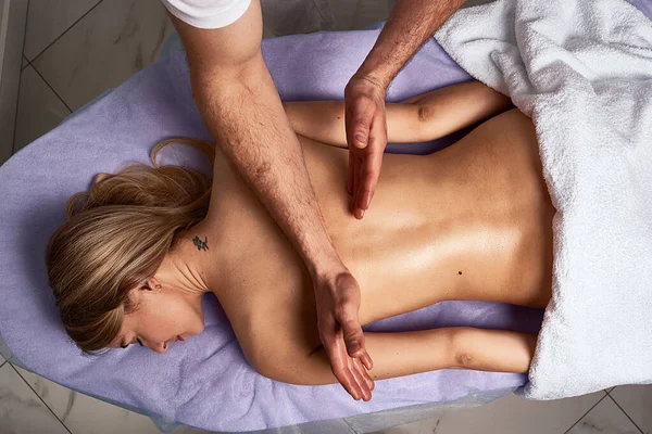 Masseur masculin faisant un massage sur un beau corps de femme nue dans le salon de spa. Concept de traitement beauté . — Photo
