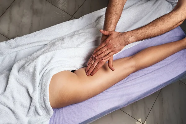 Férfi masszőr masszírozza a combját a gyönyörű meztelen női test a spa szalonban. Szépségkezelési koncepció. — Stock Fotó