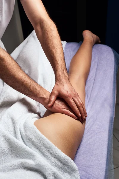 Masseur masculin faisant massage sur la cuisse de la belle femme nue corps dans le salon de spa. Concept de traitement beauté . — Photo