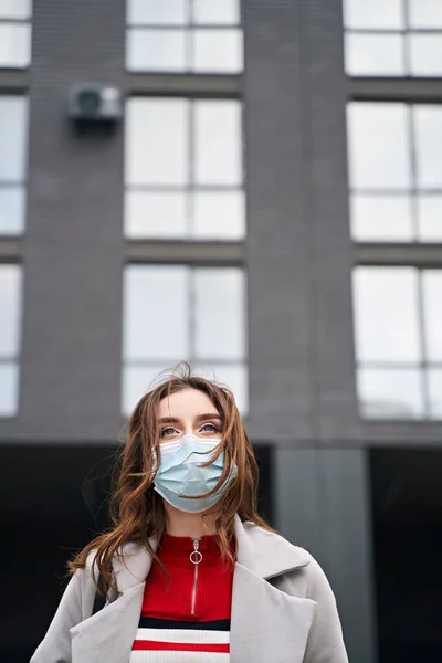 Jovem com belos olhos azuis e cabelos desgrenhados usando máscara facial de proteção contra o coronavírus COVID-19 está olhando acima com esperança. Conceito de quarentena e pandemia do coronavírus . — Fotografia de Stock