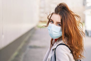 Güzel mavi gözlü, dağınık saçlı, Coronavirus MERS-Cov 'a karşı koruyucu maske takan genç bir kadın, Novel Coronavirus 2019-nCoV. Koronavirüs karantina ve pandemik konsepti.