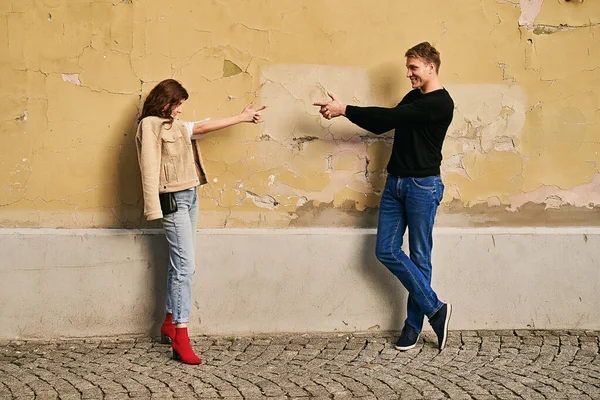 Pareja romántica joven hermosa pelirroja y alto guapo hombre rubio disparando armas de dedo entre sí — Foto de Stock