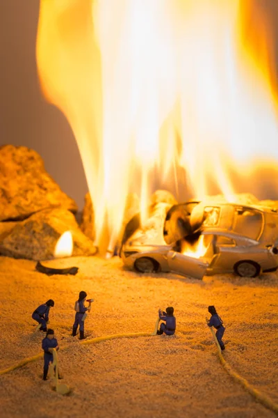 Мініатюрні пожежники на місці автокатастрофи у полум'ї — стокове фото