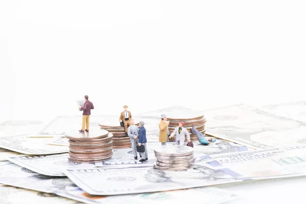 Miniature business people on coins and banknotes — Stock Photo, Image