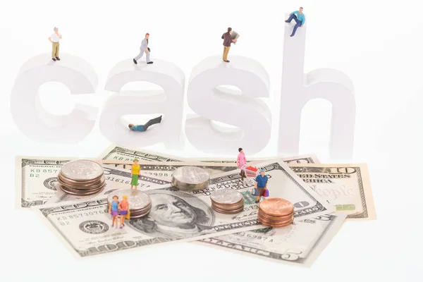 Miniature people on cash wooden letters and US banknotes — Stock Photo, Image