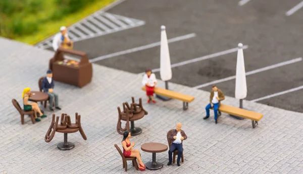 Social distancing rules with miniature people at a sidewalk cafe