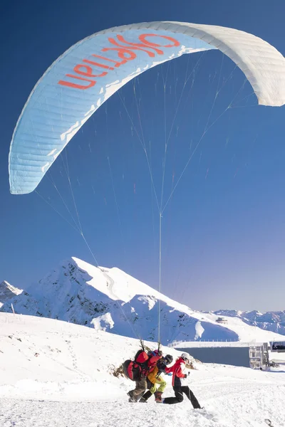 06.12.2019 Krasnaya Polyana, Rusland. Paraglider stijgt op tegen de besneeuwde bergen van de Kaukasus. — Stockfoto
