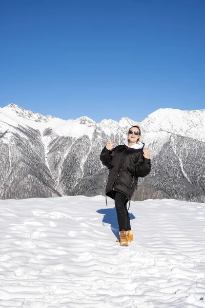 Portrait de belle fille gaie avec des lunettes. Sourire en regardant la caméra dans les montagnes en hiver — Photo