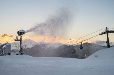 Akşam dağlarının ve teleferiğin arkasında kar topu var. Kayak sezonu için hazırlık