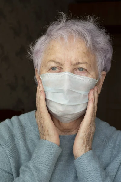 Starsza kobieta w respiratorze, zdenerwowana i przerażona. Ubrany w niebieski sweter na ciemnym tle — Zdjęcie stockowe