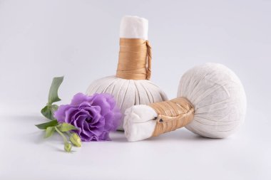 Kozmetik seti, beyaz arka planda çantalar dolusu otlar ve mor çiçeklerle masaj için..